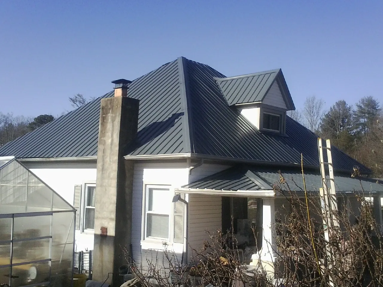 Dark blue standing seam metal roof on a white farmhouse with dormer — Slate & Tile Roof Repair by Roofing Brothers in Heppner