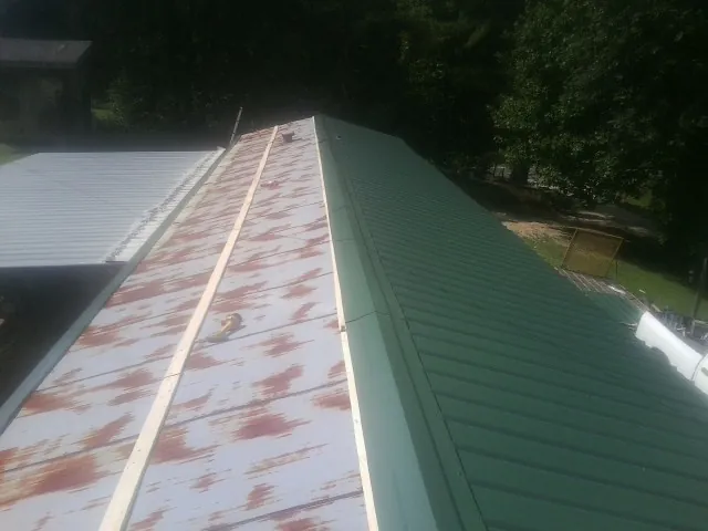 Old rusted panels beside newly installed green metal roofing — Wind Damage Roof Repair by Roofing Brothers in Heppner