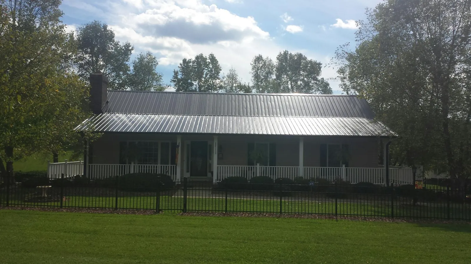 Gray metal roof on a brick ranch with a full width front porch — Gutter Guard Installation work by our crew in Heppner