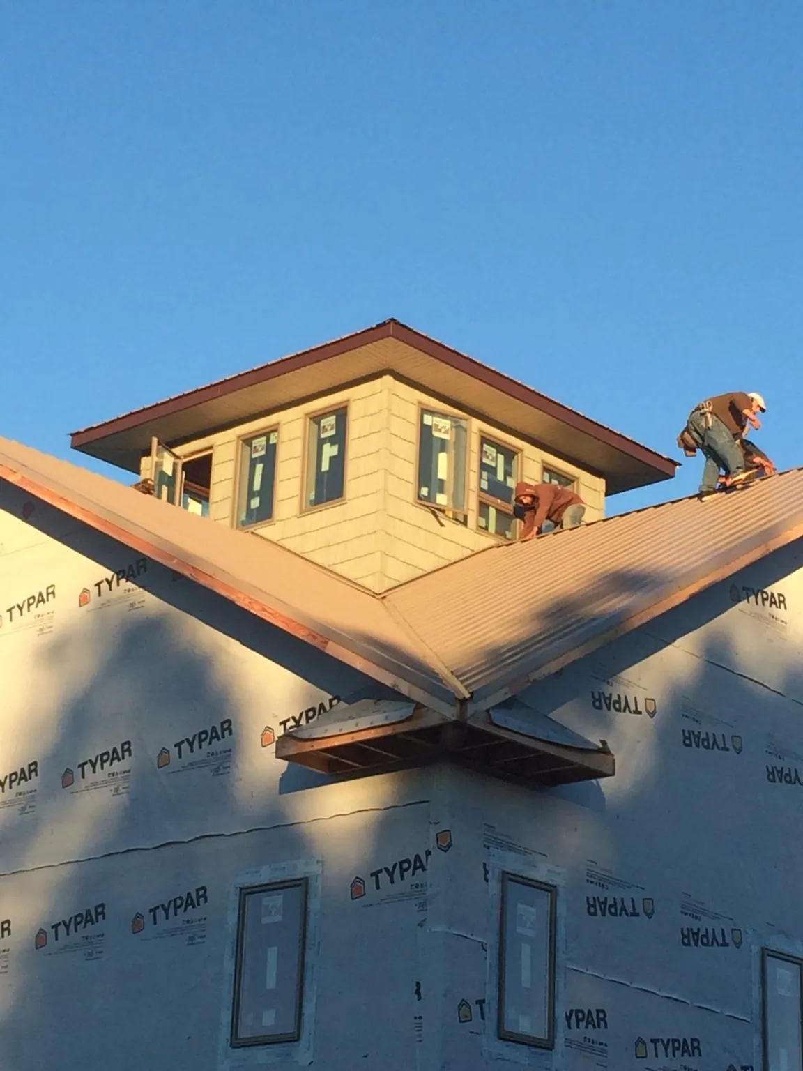 Roofers working around a rooftop cupola on a new metal roof at sunset — Roof Waterproofing in Heppner by Roofing Brothers